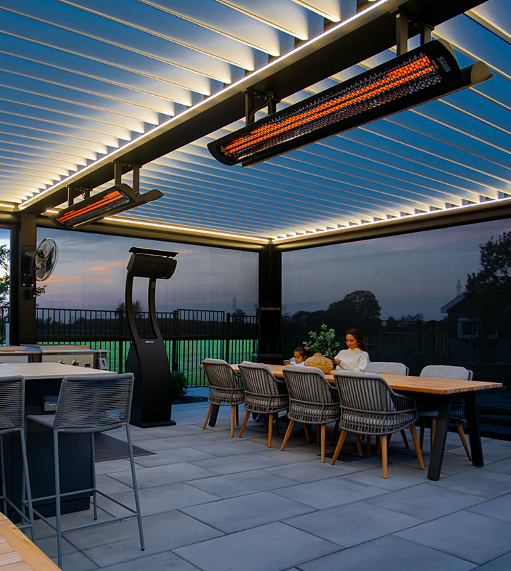 Integrated infrared heaters under a modern louvered pergola with outdoor kitchen and dining area