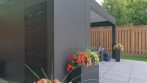 Painted storage door on an Umbra Grey pergola with storage, colour-matched to the aluminum frame.