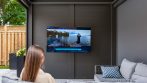 Swing-out wall-mounted television on the aluminum wall of a shed pergola.