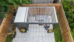 Overhead view of a small backyard shed with pergola, louvered aluminum roof and paver patio.