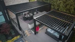 Aerial view of a modern backyard pergola design: two black louvered pergolas on a two-tier deck, dining area above and hot tub below