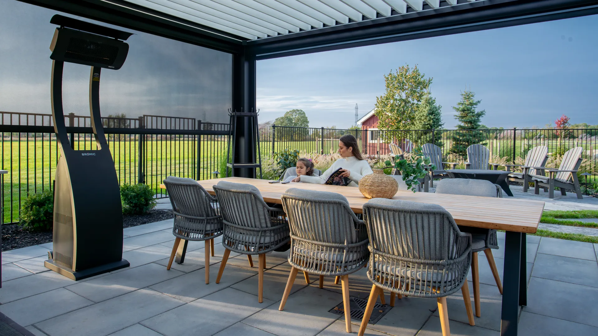 Dining table under a louvered pergola with a lowered ZIP screen and a freestanding patio heater on a stone patio