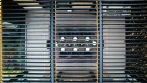 Top view through the open louvers of a pergola over a dining table set for dinner, with LED strips along the beams